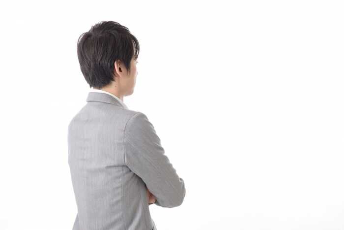 腕を組んで考えている男性